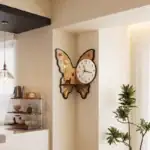 Horloge murale en forme de papillon avec décor floral et animal, design élégant pour décoration intérieure.