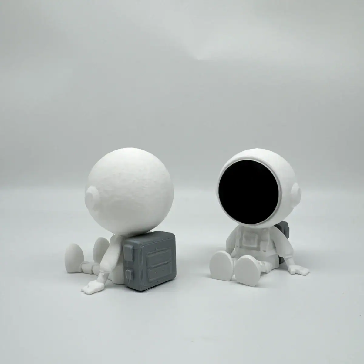 Figurines d'astronautes minimalistes en blanc, assis sur un fond blanc, avec un design épuré et moderne, parfaites pour la décoration scientifique ou thématique.