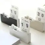 Porte-documents calendrier en bois blanc avec affichage de dates, jours et mois, idéal pour organiser votre bureau ou espace de travail avec style et élégance.