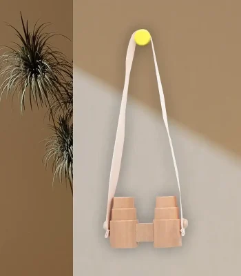 Lunette de vision en bois suspendue avec bande en tissu blanc, fixée au mur avec un bouton jaune, décoration minimaliste et naturelle.
