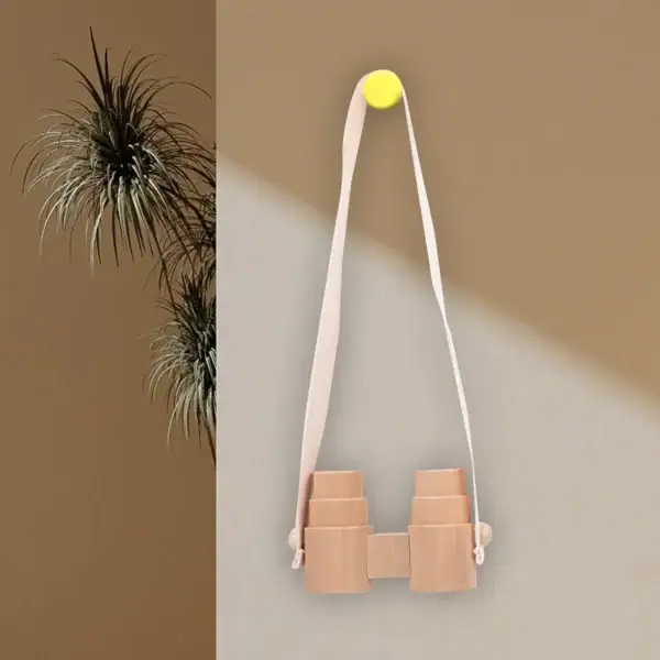 Lunette de vision en bois suspendue avec bande en tissu blanc, fixée au mur avec un bouton jaune, décoration minimaliste et naturelle.
