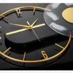 Horloge murale design noir et or avec aiguilles dorées, idéale pour une décoration intérieure élégante et contemporaine.