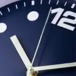 Close-up d'une horloge scientifique avec un cadran bleu foncé, des chiffres blancs et des aiguilles argentées indiquant l'heure, illustrant la précision et la technologie.