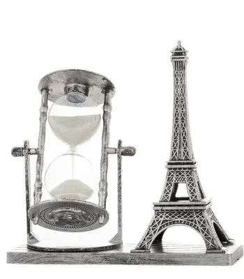 Sablier avec la Tour Eiffel miniature, symbole de la science et du voyage dans le temps, sur une base en bois.