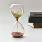 Balancier de sablier avec liquide doré et rose, symbole de la science et du temps.