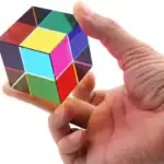 Cube de Rubik multicolore tenu entre les doigts d'une main, illustrant un jeu de réflexion scientifique et de puzzle.