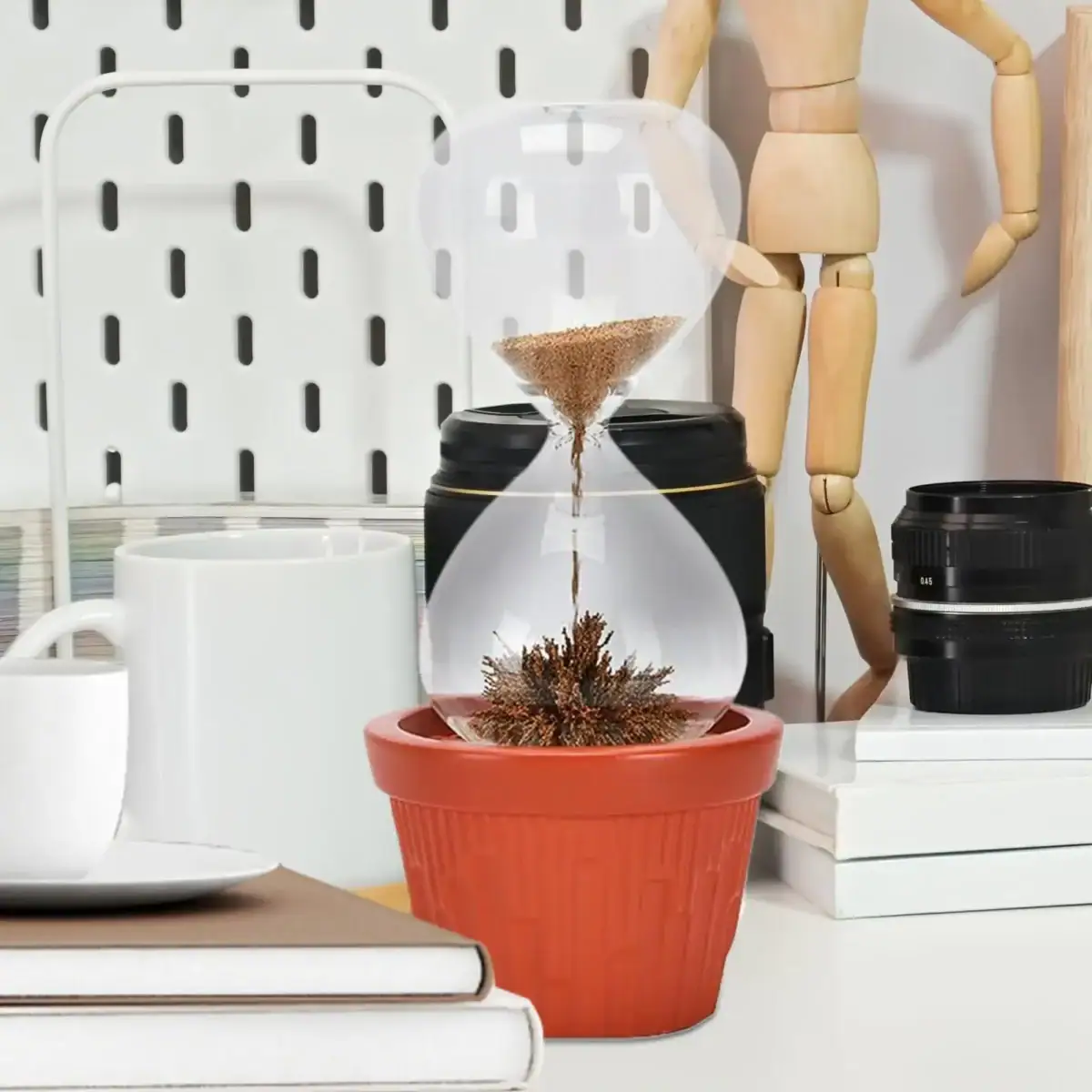 Ampoule avec sable et plante sèche dans un pot en terre cuite.