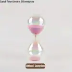 Un sablier coloré en verre avec du sable rose, illustrant un temps de flux de sable de 30 minutes.