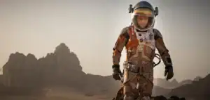 Explorateur en combinaison spatiale dans un paysage désertique avec montagnes en arrière-plan.