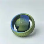 Miniature de globe terrestre insérée dans une balle de tennis, illustrant la fusion entre sport et géographie.