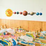 Décoration murale représentant le système solaire dans une chambre d'enfant, avec des modèles des planètes et du soleil, apportant une touche éducative et ludique à l'espace.