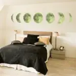 Décoration murale représentant différentes phases de la lune au-dessus du lit dans une chambre moderne et élégante.