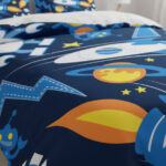 Vêtement de lit avec motifs spatiaux pour enfants, illustrant planètes, étoiles, fusées et astronautes, parfait pour une chambre à thème scientifique ou astronomique.