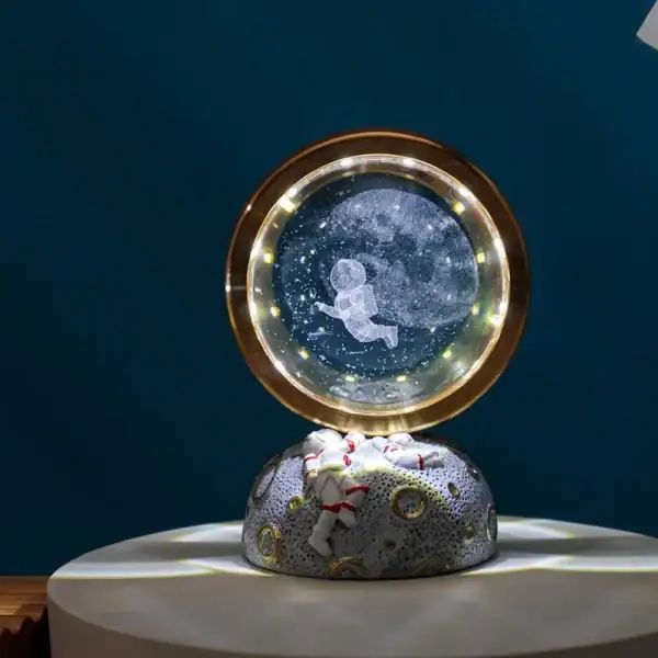 Boule à neige décorative représentant un astronaute flottant dans l'espace, avec un fond étoilé et un éclairage LED intégré. Parfaite pour les amateurs de science et de décoration originale.