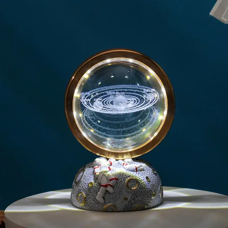 Globe terrestre décoratif avec anneaux lumineux représentant le système solaire, posé sur une roche décorative, dans un environnement intérieur.