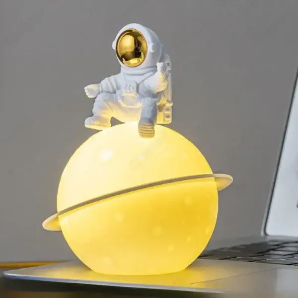 Vaisseau spatial décoratif avec astronaute en costume blanc et casque doré, posé sur une planète lumineuse jaune, idéal pour la décoration scientifique ou thématique.