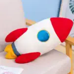 Peluche en forme de vaisseau spatial avec couleurs vives, idéale pour la décoration ou comme jouet éducatif pour enfants passionnés d'espace.