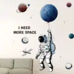 Illustration d'un astronaute en costume spatial tenant un ballon représentant une planète, avec d'autres planètes et un satellite dans un décor mural inspiré de l'espace.