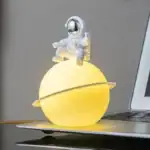 Vêtement d'astronaute miniature posé sur une planète lumineuse avec anneau, décor de science-fiction.
