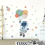 Un astronaute en costume spatial flotte dans un décor de mur avec des planètes en ballon, étoiles et fusée, créant une ambiance ludique et éducative sur le thème de l'espace.