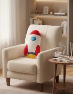 Peluche de vaisseau spatial rouge et blanc avec détails bleus et jaunes, posée sur un fauteuil beige dans un salon moderne.