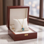 Collier en or avec pendentif représentant une planète, présenté dans une élégante boîte en bois pour bijoux. Parfait pour les amateurs de science et d'astronomie.