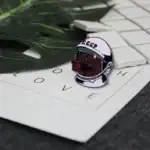 Poinçon en forme de tête de loup portant un casque spatial avec inscription "CCCP", posé sur une feuille avec des lettres "LOVE" et des pièces de jeu d'échecs en arrière-plan.