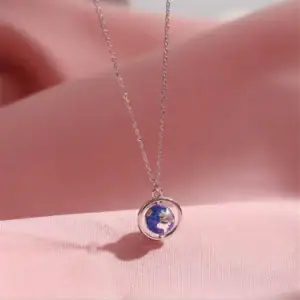 Collier avec pendentif globe terrestre miniature en argent, symbole de voyage et de découverte.