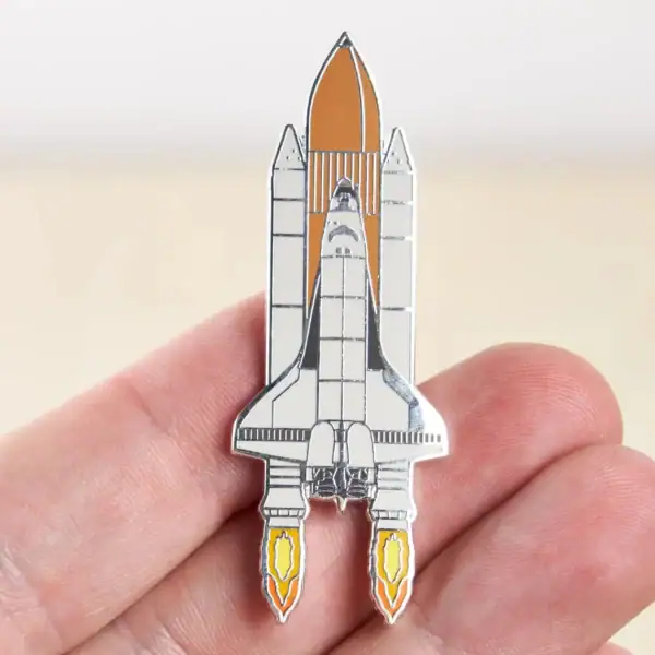 Pin's en forme de vaisseau spatial avec détails en métal, illustrant une fusée prête à décoller, parfait pour les amateurs d'astronomie et de science.