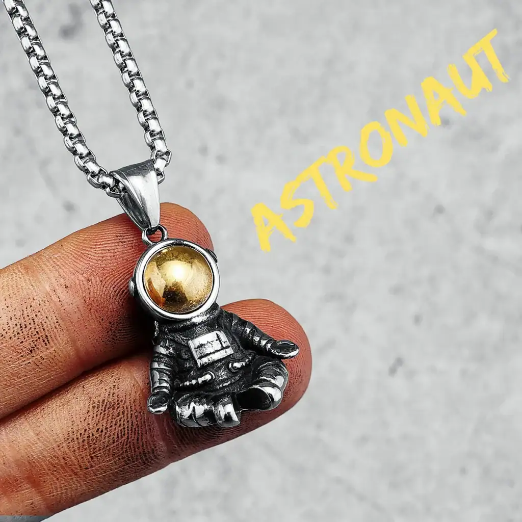 Collier avec pendentif d'astronaute en métal argenté et boule dorée, inspiré de l'espace et de l'exploration spatiale.