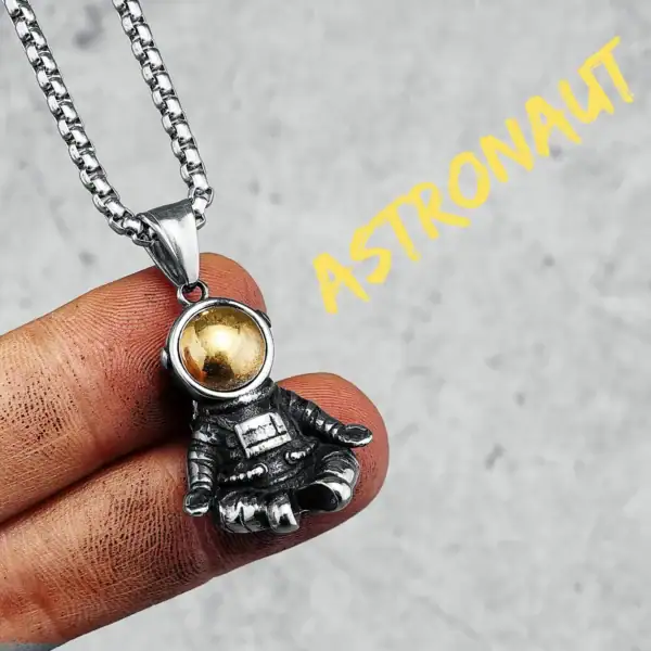 Collier avec pendentif d'astronaute en métal argenté et boule dorée, inspiré de l'espace et de l'exploration spatiale.