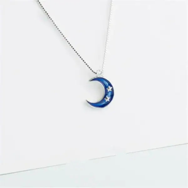 Pendentif en forme de lune bleue avec étoiles, suspendu à une chaîne fine.