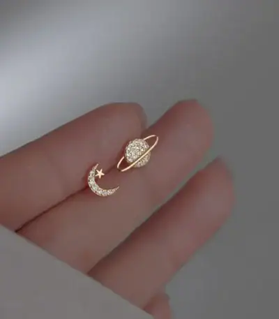 Bijou d'oreille en forme de lune et d'étoile ornée de diamants, symbolisant la celestialité et l'élégance.