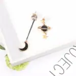 Épingles d'oreilles avec motifs planètes et lune, design cosmique élégant.