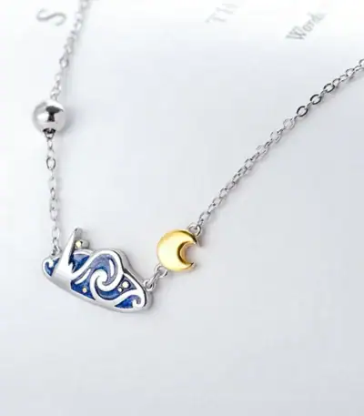 Collier délicat avec pendentif lune en or et constellation en argent, parfait pour les amateurs d'astronomie et de sciences.