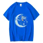 T-shirt bleu avec un motif d'astronaute flottant dans l'espace, entouré de planètes, étoiles et une lune stylisée. Parfait pour les amateurs de science et d'astronomie.