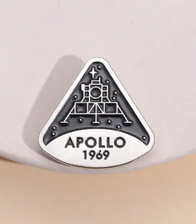 Une broche ou badge représentant la mission Apollo 11 de la NASA, avec la date 1969, symbole emblématique de l'exploration spatiale.