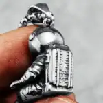Pendentif en forme d'astronaute en métal argenté, détaillé avec un casque et un sac à dos, parfait pour les amateurs d'espace et de science.