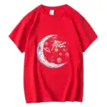 T-shirt rouge avec illustration d'une astronaute flottant près d'une lune stylisée, entourée de planètes et d'étoiles, parfait pour les amateurs d'espace et de science.