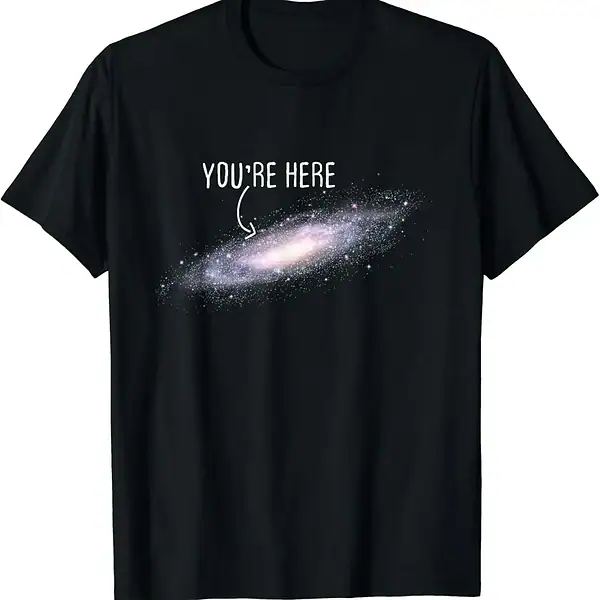 T-shirt galaxie avec texte "You're Here" en blanc sur fond noir, représentant une galaxie spirale avec un message humoristique et cosmique.