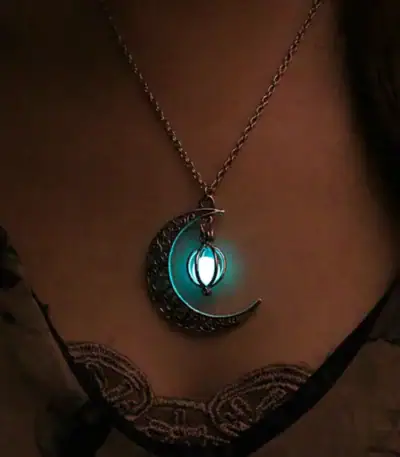 Pendentif lune et étoile lumineux suspendu à une chaîne, illuminant doucement dans l'obscurité, idéal pour la décoration ou comme bijou original.