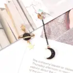 Boucles d'oreilles pendantes avec motifs planètes et lune en métal doré et noir.