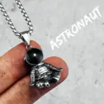 Pendentif astronaute en métal avec boule noire, suspendu à une chaîne en acier inoxydable, idéal pour les amateurs d'astronomie et de science.
