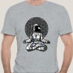 T-shirt gris avec illustration d'astronaute assis devant un motif géométrique complexe, style artistique moderne et scientifique.