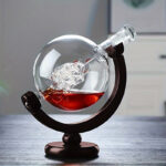 Globe en verre contenant un liquide rouge et un objet scientifique, posé sur un support en bois, décoratif et éducatif.