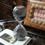 Sablier en verre transparent avec grains de sable noirs, décoration élégante et vintage pour un intérieur sophistiqué.