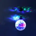 Lampe suspendue en forme de boule projetant des lumières colorées sur le plafond, créant une ambiance lumineuse et artistique.