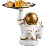 Porte-savon original en forme d'astronaute blanc avec casque doré, tenant un plateau de bonbons colorés. Idéal pour une décoration de salle de bain ludique et spatiale.