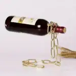 Bouteille de vin suspendue avec chaîne en or et corde en jute, décoration originale pour un intérieur scientifique ou industriel.