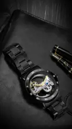 Montre mécanique noire avec mouvement visible, bracelet en acier et détails dorés, alliant élégance et précision pour les amateurs de science et de design.
